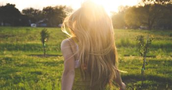 Frau läuft auf einer Wiese durch die Sonne