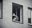 Frau sitzt am Fenster und denkt nach