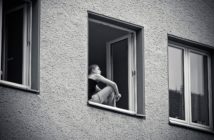 Frau sitzt am Fenster und denkt nach