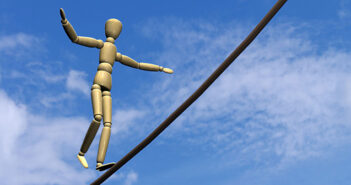 Eine Holz-Gliederpuppe balanciert auf einem Seil