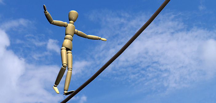 Eine Holz-Gliederpuppe balanciert auf einem Seil