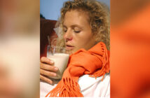 Eine erkältete Frau trinkt ein Glas heiße Milch