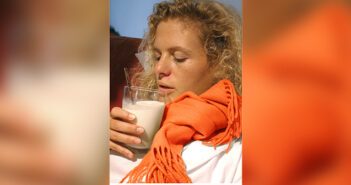 Eine erkältete Frau trinkt ein Glas heiße Milch