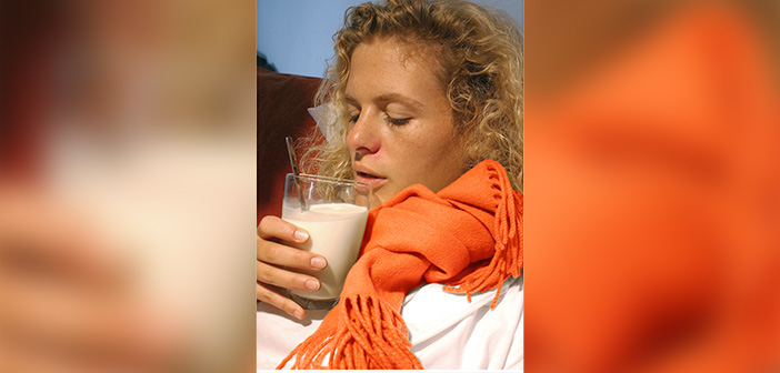 Eine erkältete Frau trinkt ein Glas heiße Milch