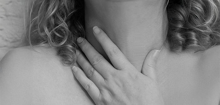 Eine Frau greift sich an den Hals