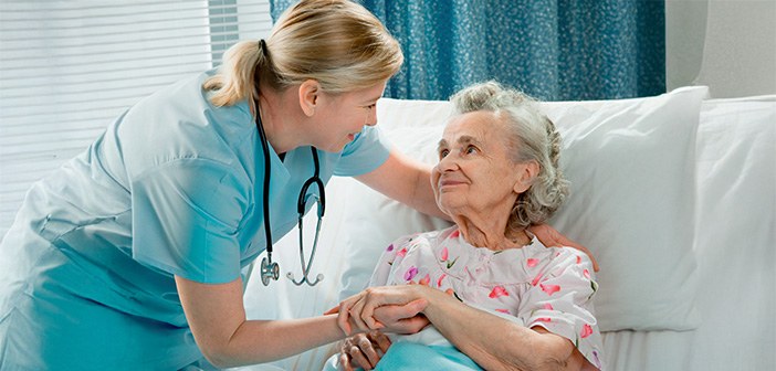 Eine Krankhausbedienstete kümmert sich um eine ältere Frau, die in einem Krankenbett liegt.