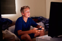 Ein etwa 12-jähriger Junge sitzt vor einem Monitor und spielt ein Videospiel.