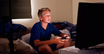 Ein etwa 12-jähriger Junge sitzt vor einem Monitor und spielt ein Videospiel.