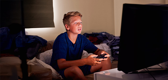Ein etwa 12-jähriger Junge sitzt vor einem Monitor und spielt ein Videospiel.