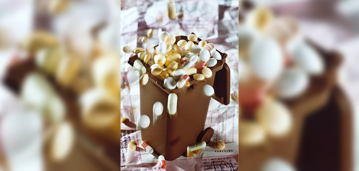 Symbolbild: Viele verschiedenfarbige Tabletten werden in eine Miniaturmülltonne geschüttet